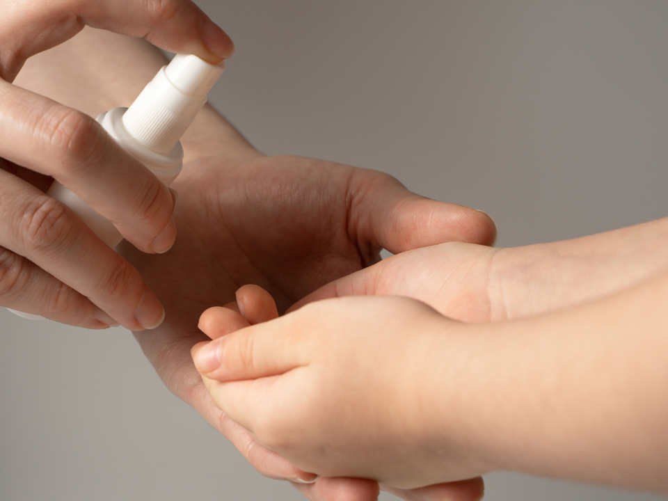 Un adulto disinfetta con il gel igienizzante la manina di un bambino