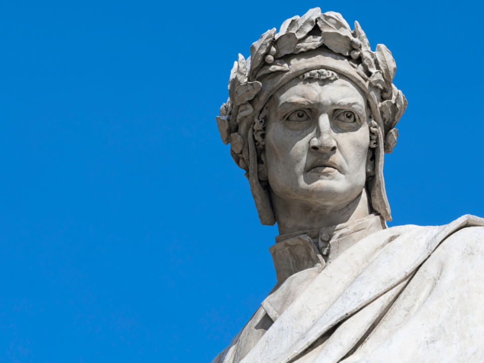 Statua di Dante Alighieri con corona di alloro, ripresa dal basso contro un cielo azzurro