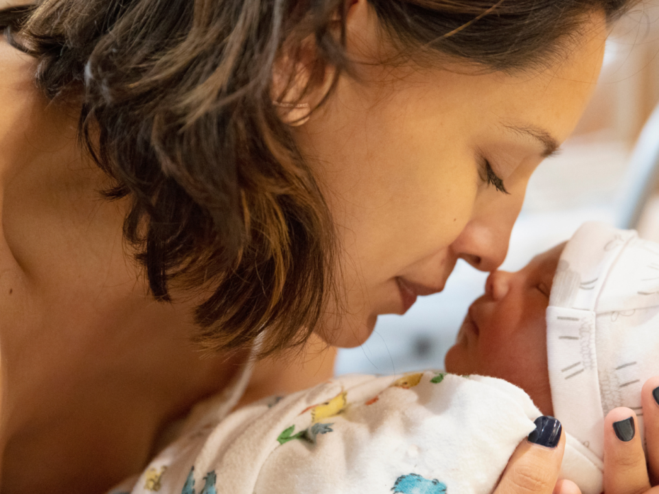 Una madre tiene in braccio il suo neonato guancia a guancia
