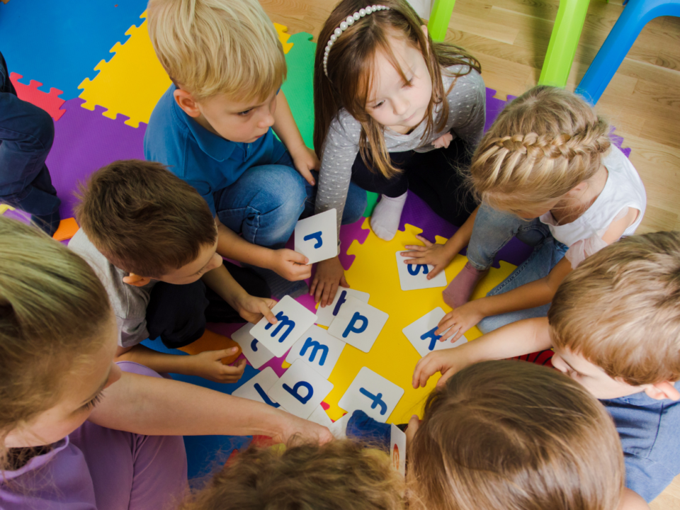 Bambini e un'insegnante giocano con carte alfabetiche colorate sedute in cerchio
