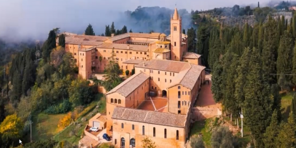 Slide del progetto «Feel Green» per la transizione ecologica, con veduta aerea del monastero di Monte Oliveto Maggiore