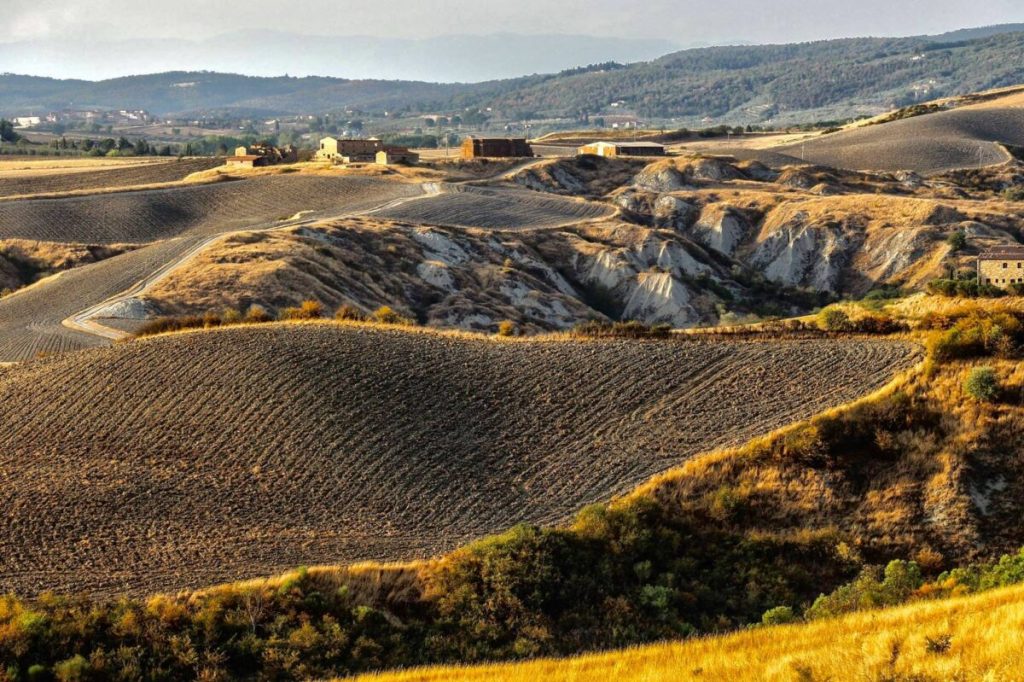 Paesaggio collinare delle Crete Senesi, con campi arati e casolari in Toscana
