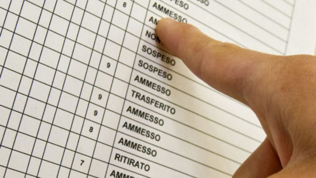 Primo piano di un registro scolastico con un dito che indica la dicitura "Ammesso"