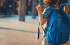 Bambino con zaino blu visto di spalle mentre si avvia verso scuola